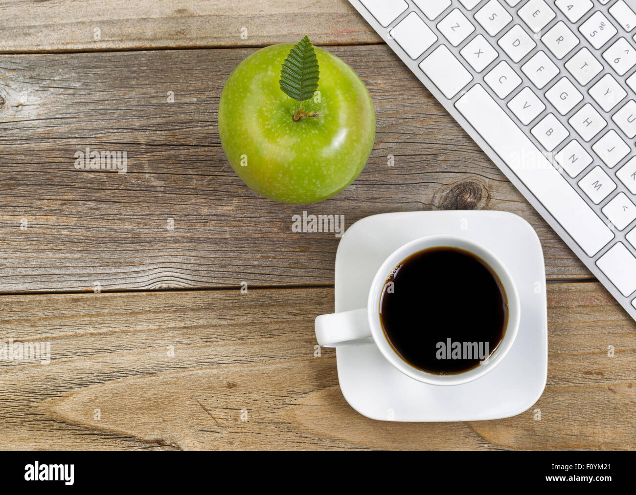 Vue de dessus de la pomme verte, selective focus on top leaf et café, café noir avec clavier ordinateur partielle sur bois rustique. Banque D'Images