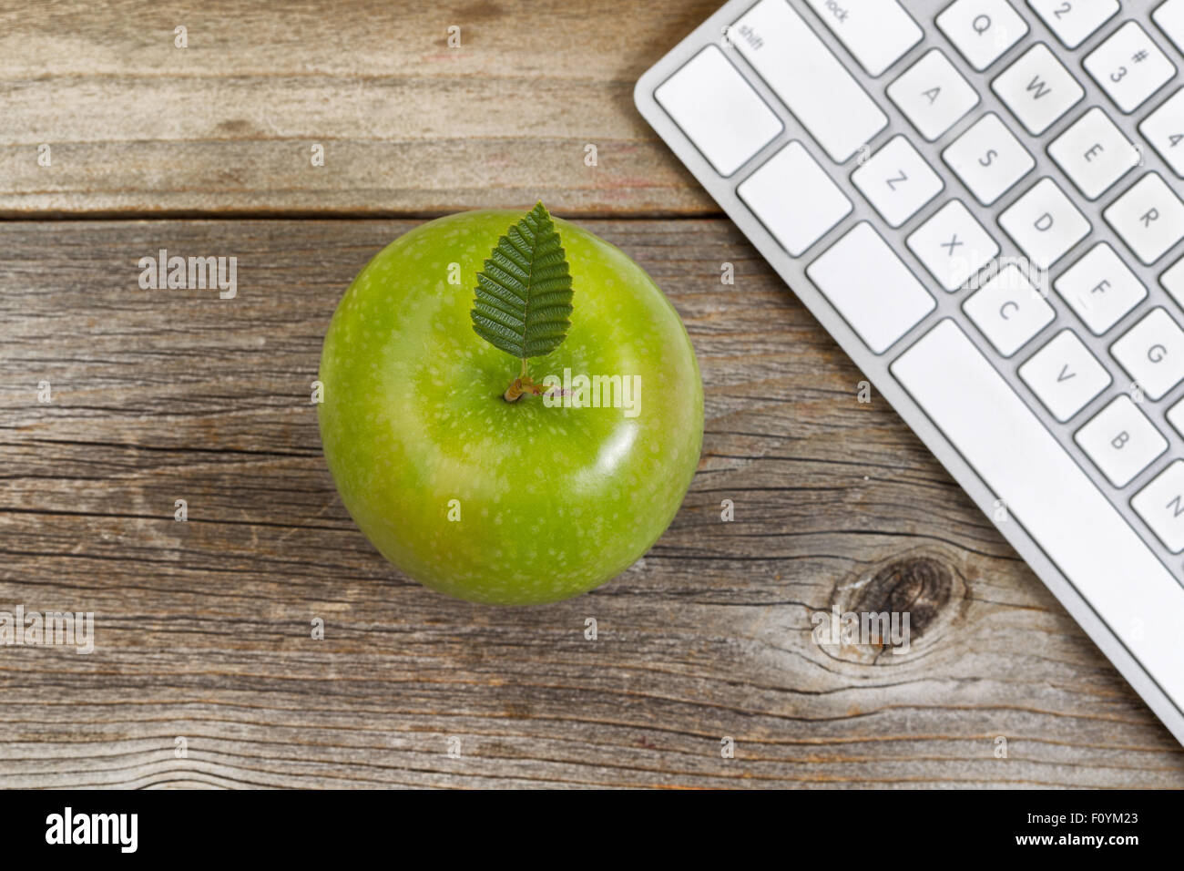 Vue de dessus de la pomme verte, selective focus sur le dessus des feuilles, avec vue partielle sur le clavier de l'ordinateur en bois rustique. Banque D'Images