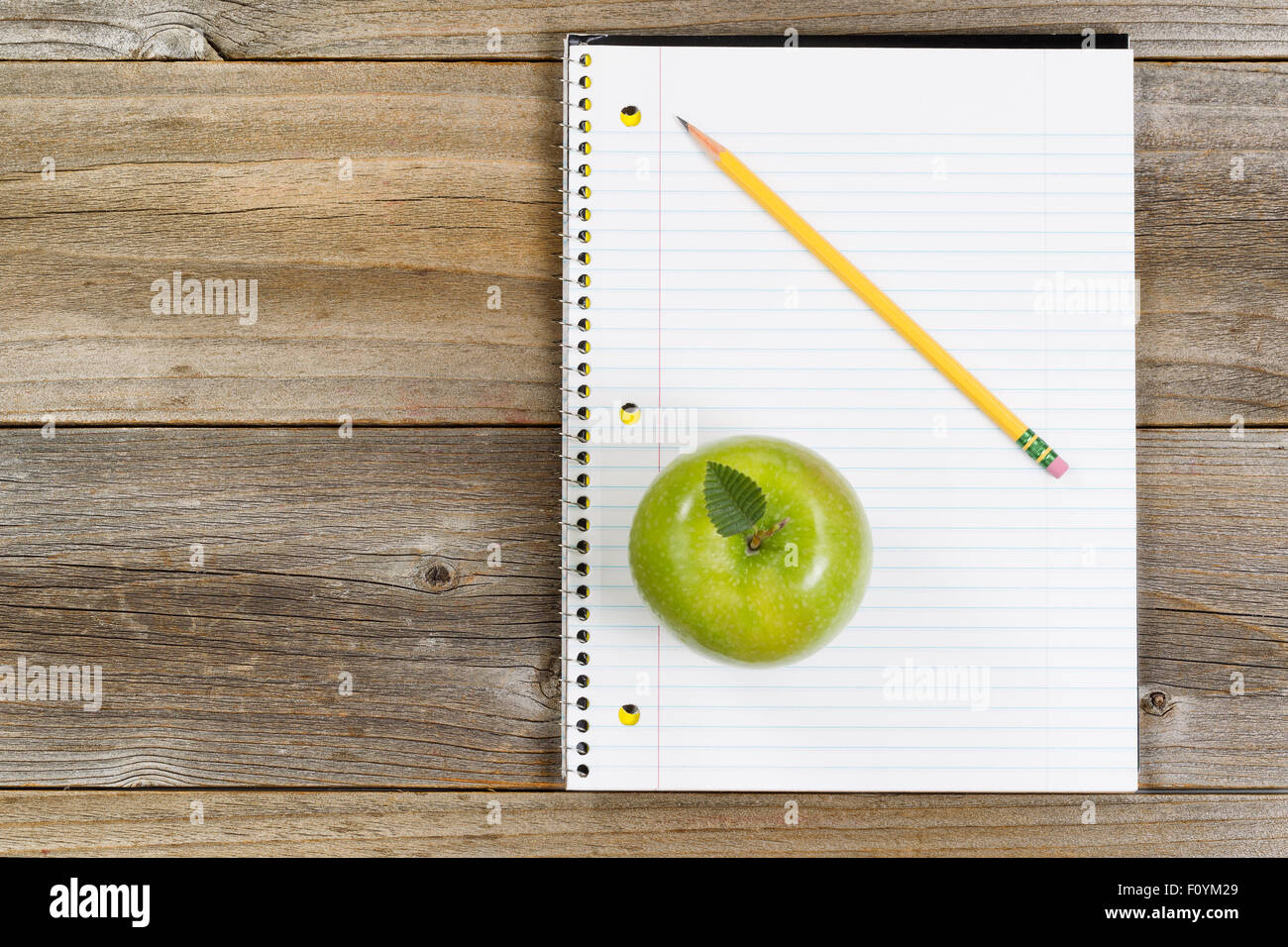 Vue de dessus de la pomme verte, le bloc-notes et crayon sur bois rustique. Banque D'Images