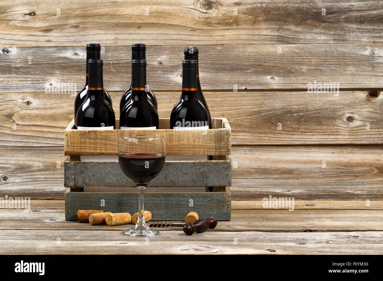 Verre de vin rouge avec plein de bouteilles En caisse bois, ancien tire-bouchon et utilisé des bouchons sur les planches de bois rustique. Banque D'Images