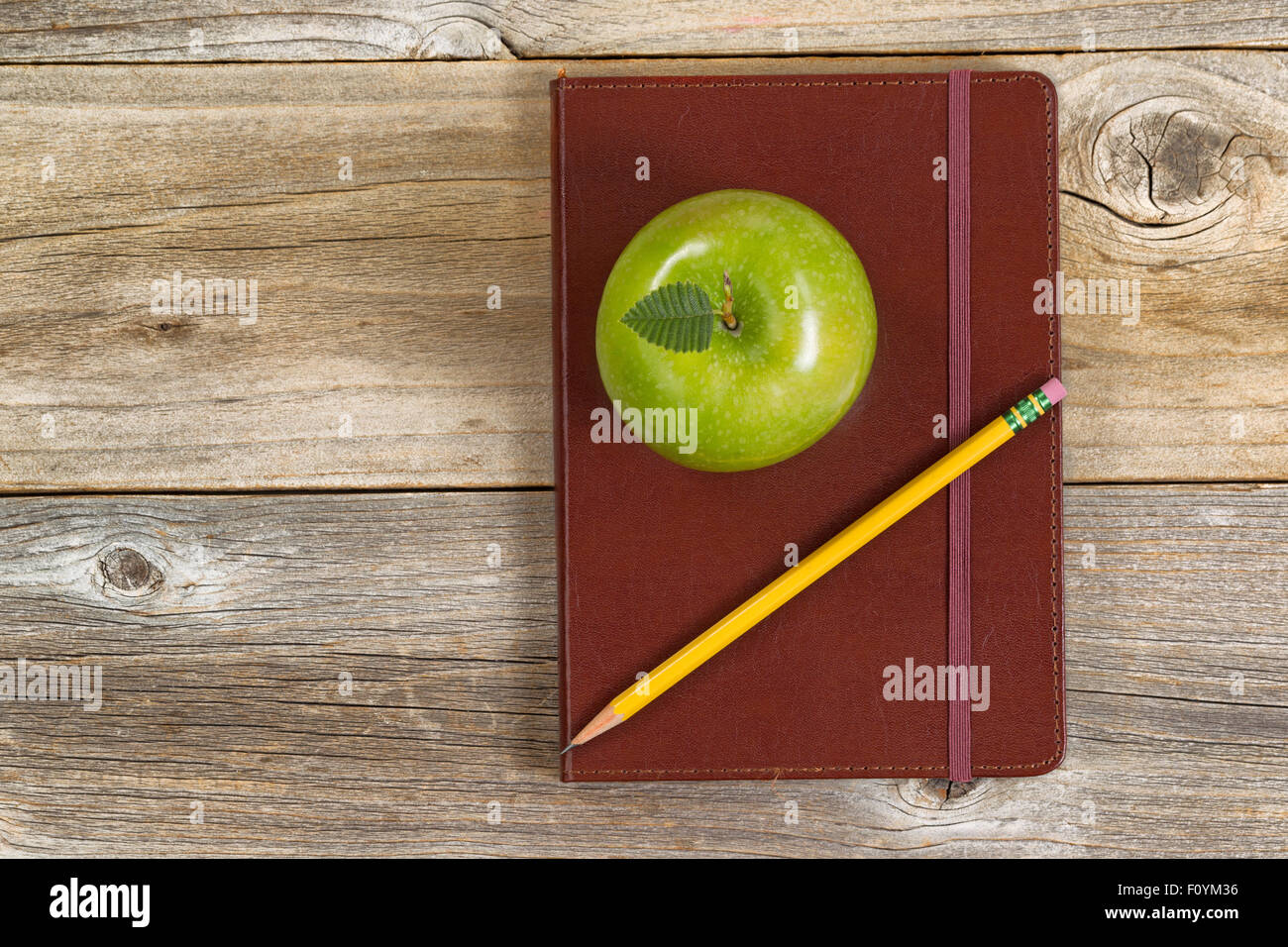 Vue de dessus en cuir vert pomme, le bloc-notes et crayon sur bois rustique. Banque D'Images