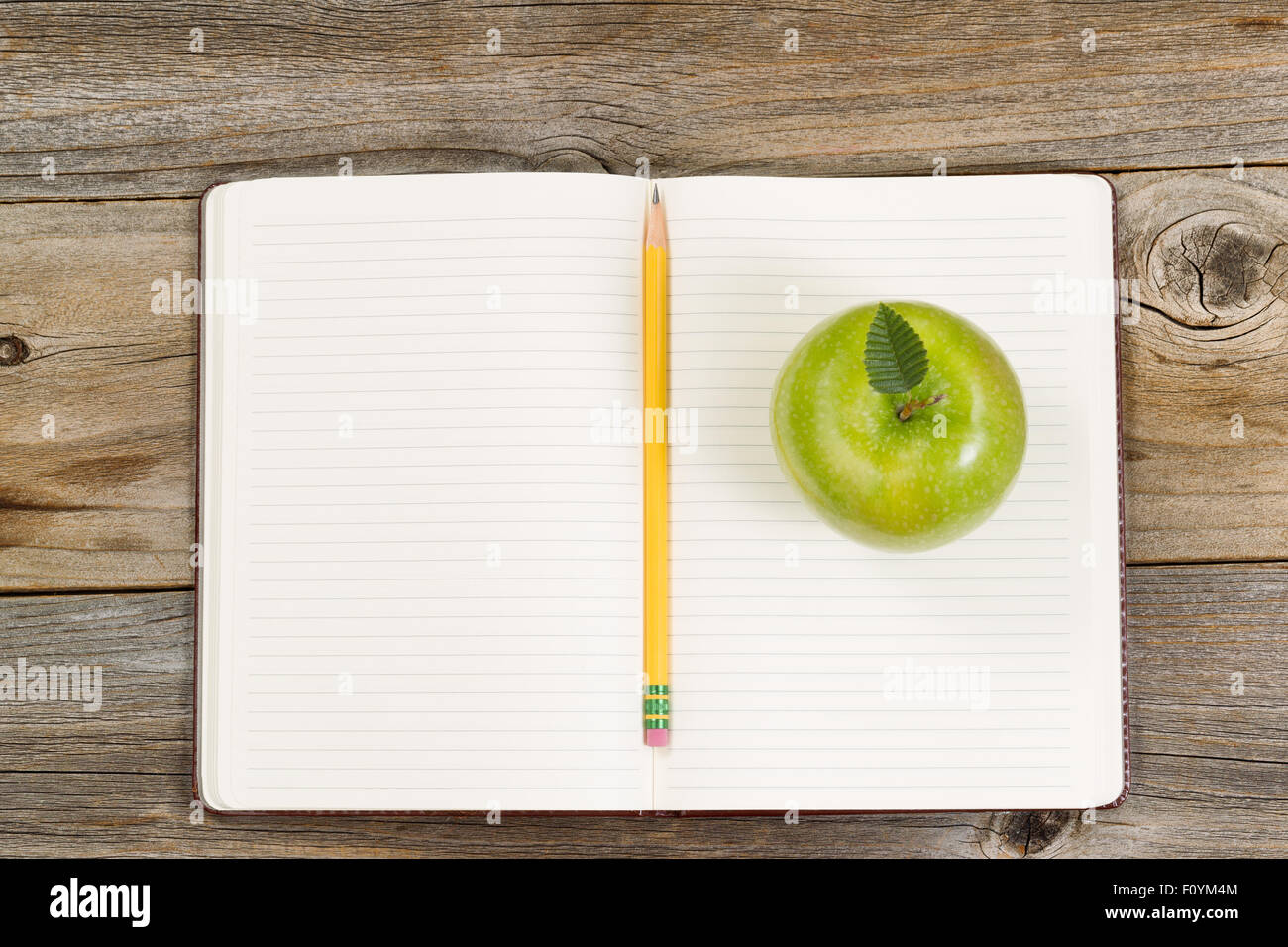 Vue de dessus de la pomme verte, ouvrez le bloc-notes avec crayon en bois rustique sur centre. Banque D'Images