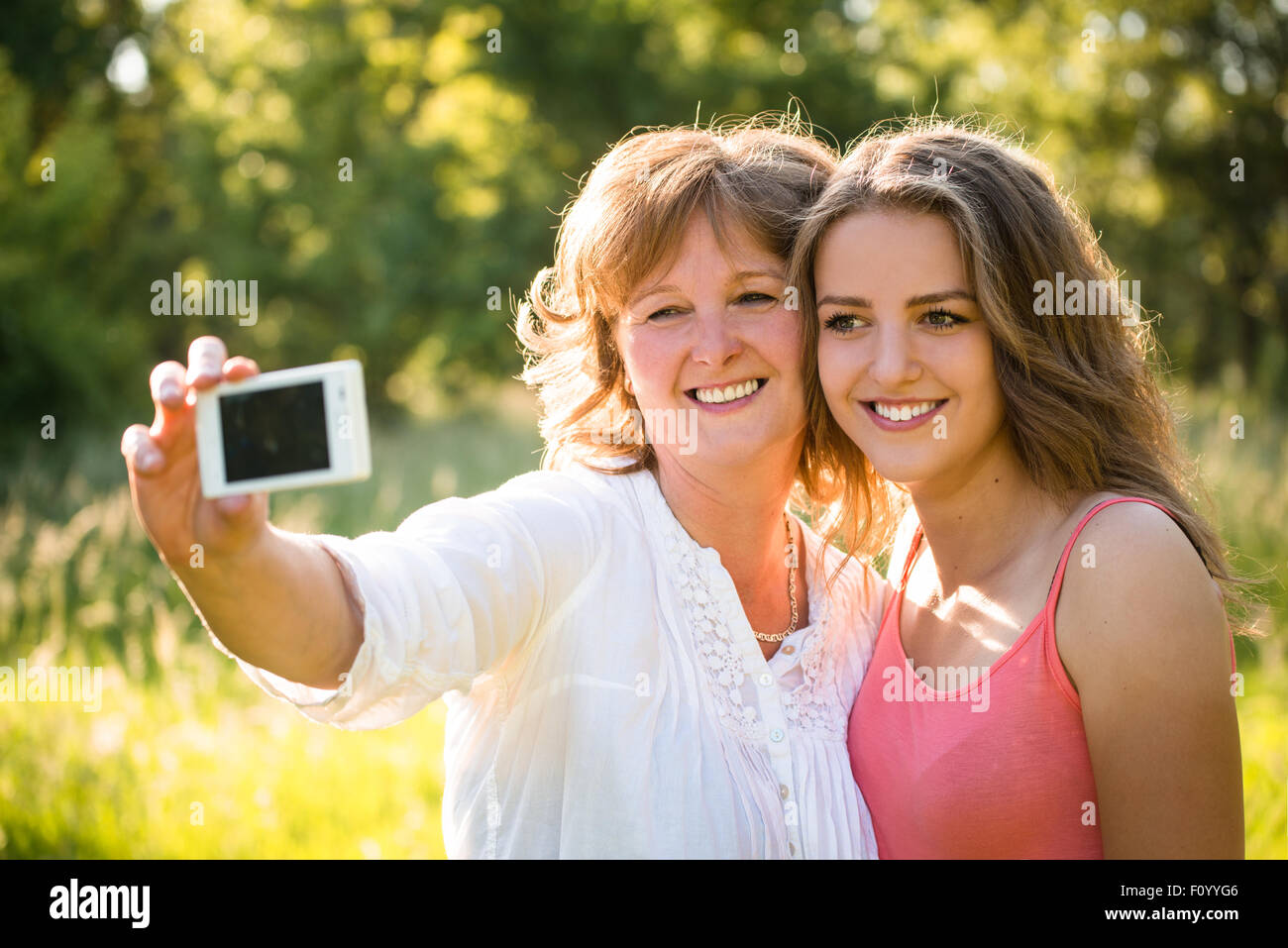 Fille adolescente et son mère prennent des photos avec un téléphone mobile selfies Banque D'Images