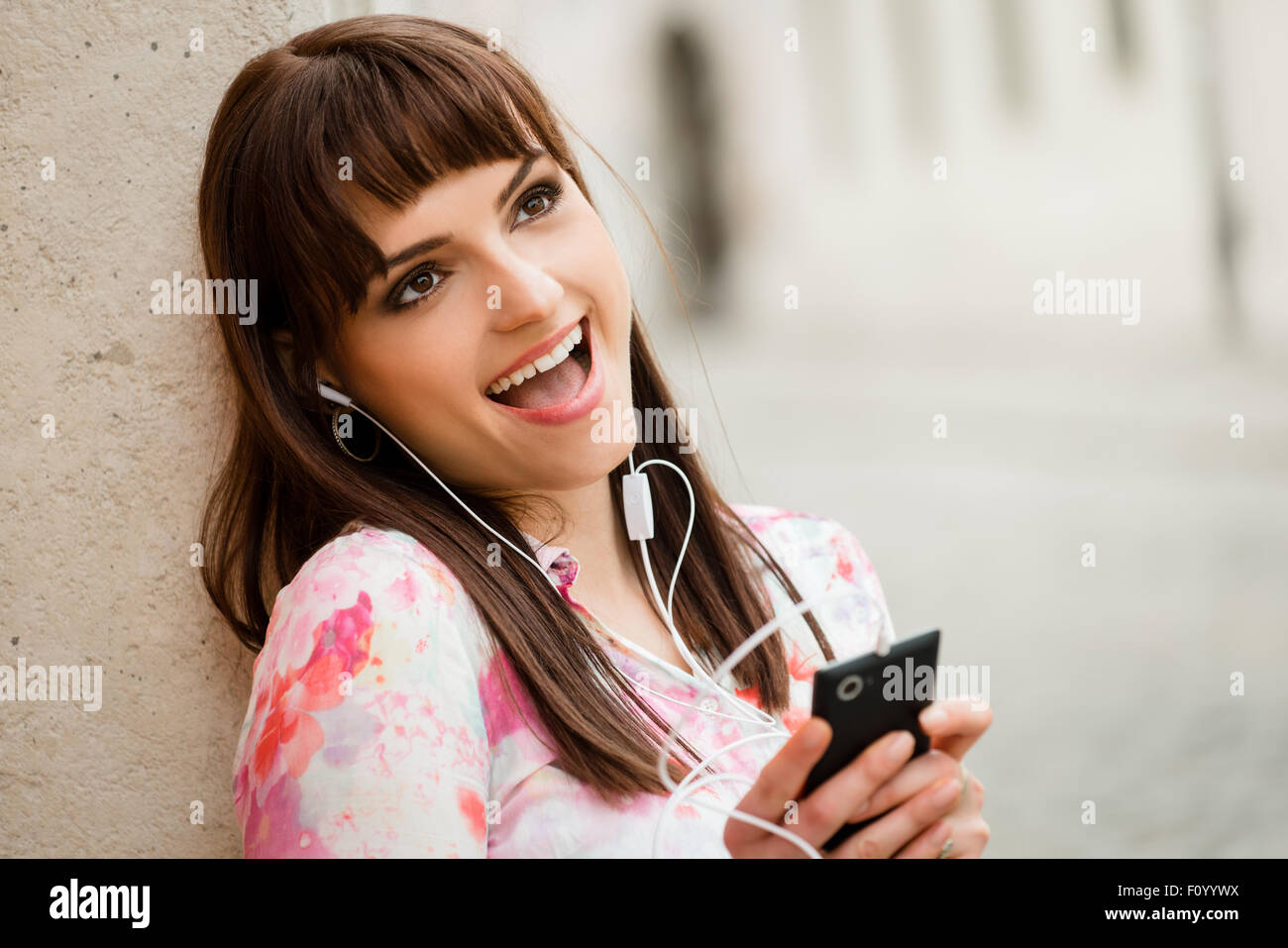 Jeune femme chantant de la musique elle est à l'écoute de votre téléphone mobile en street Banque D'Images