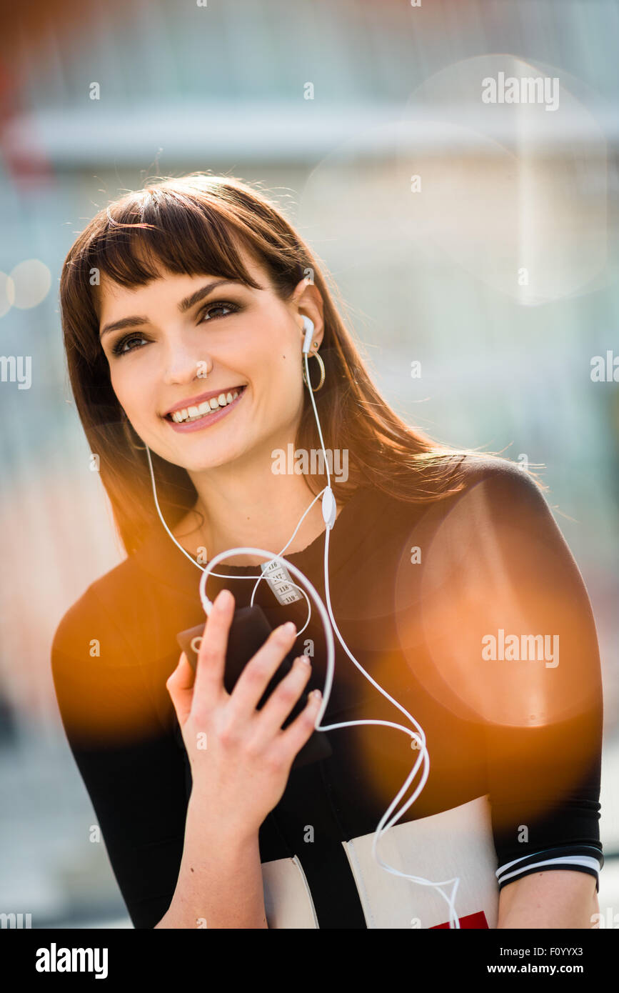 Jeune femme avec téléphone mains libres dans street - réflexions poussées visible Banque D'Images