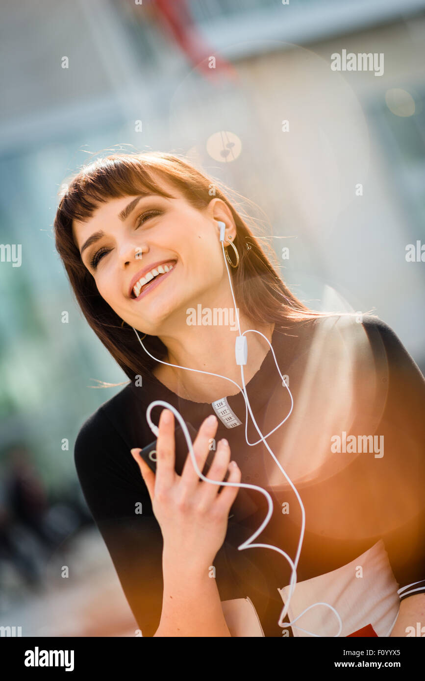 Jeune femme avec téléphone mains libres dans street - réflexions poussées visible Banque D'Images