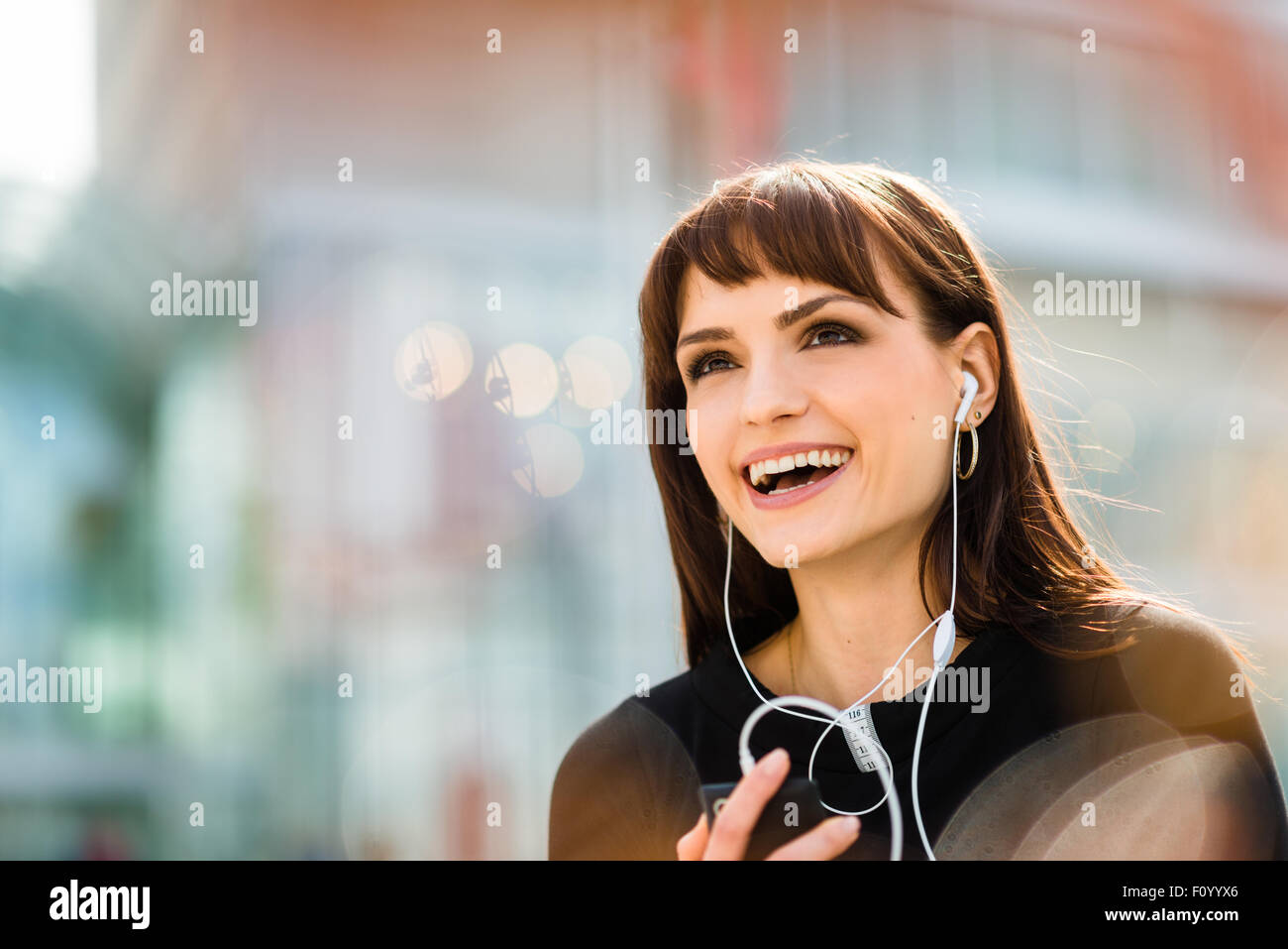 Jeune femme avec téléphone mains libres et rire - Piscine dans Street Banque D'Images