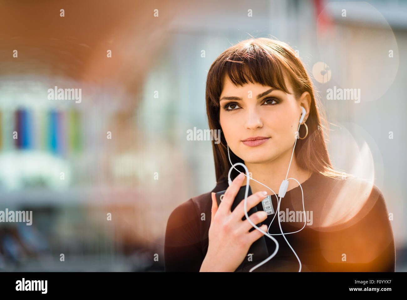 Jeune femme avec téléphone mains libres dans street - réflexions poussées visible Banque D'Images