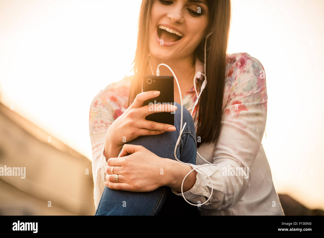 Détail de young woman listening music à partir de son téléphone et le chant en street avec en arrière-plan Banque D'Images