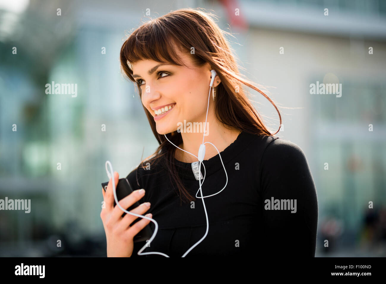 Jeune femme avec téléphone mains libres dans Street Banque D'Images