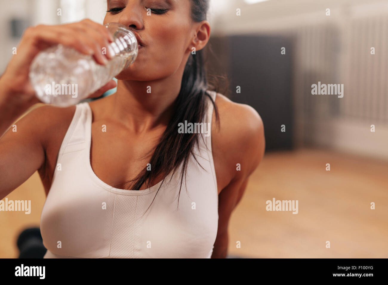 Close up shot of woman remise en forme de l'eau potable dans une pause. Jeune femme à gym fitness prend une pause après la formation. Banque D'Images
