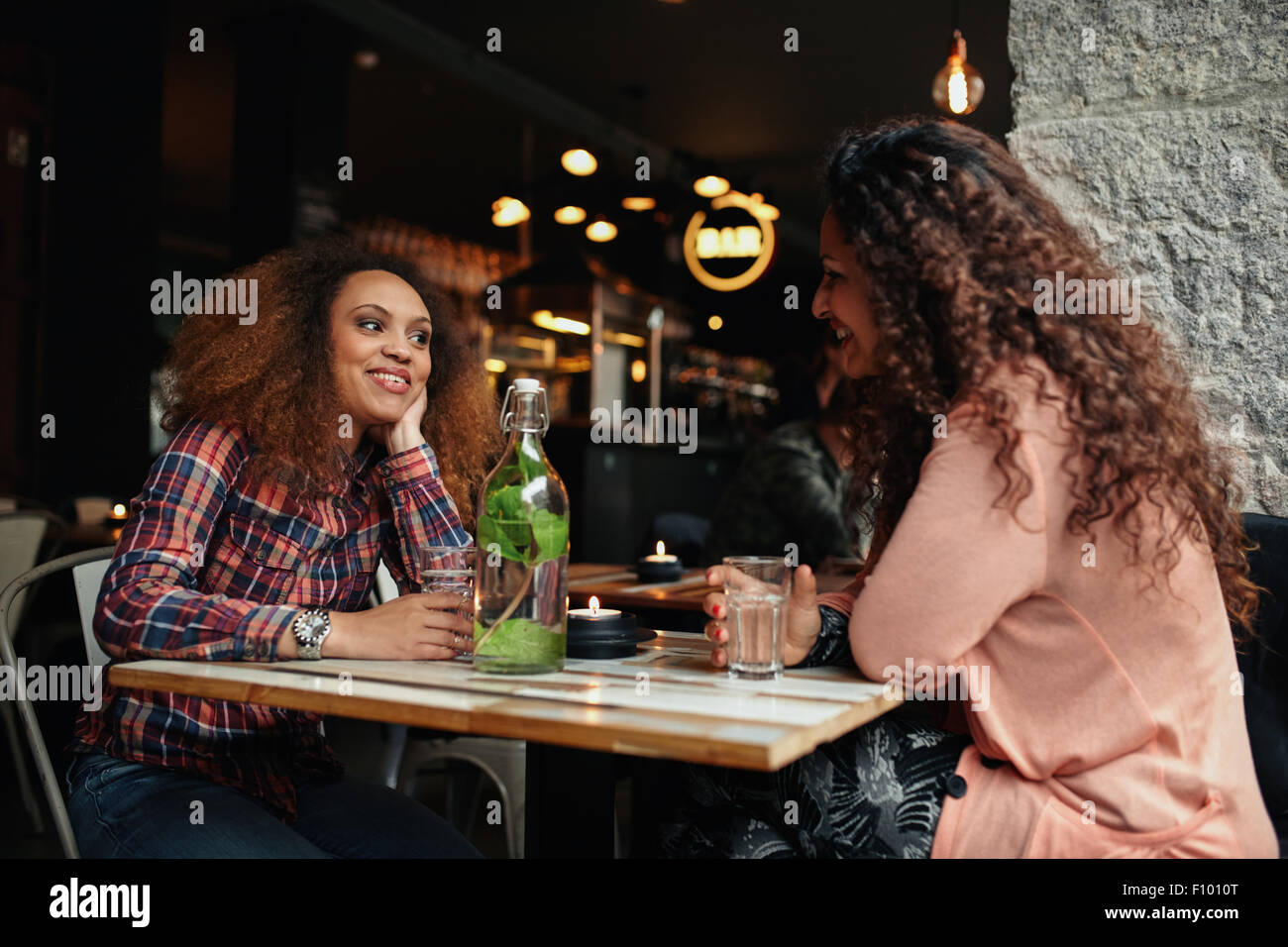 Photo de deux jeunes femmes assises dans un restaurant à parler. Happy young female friends rencontre dans un café. Banque D'Images