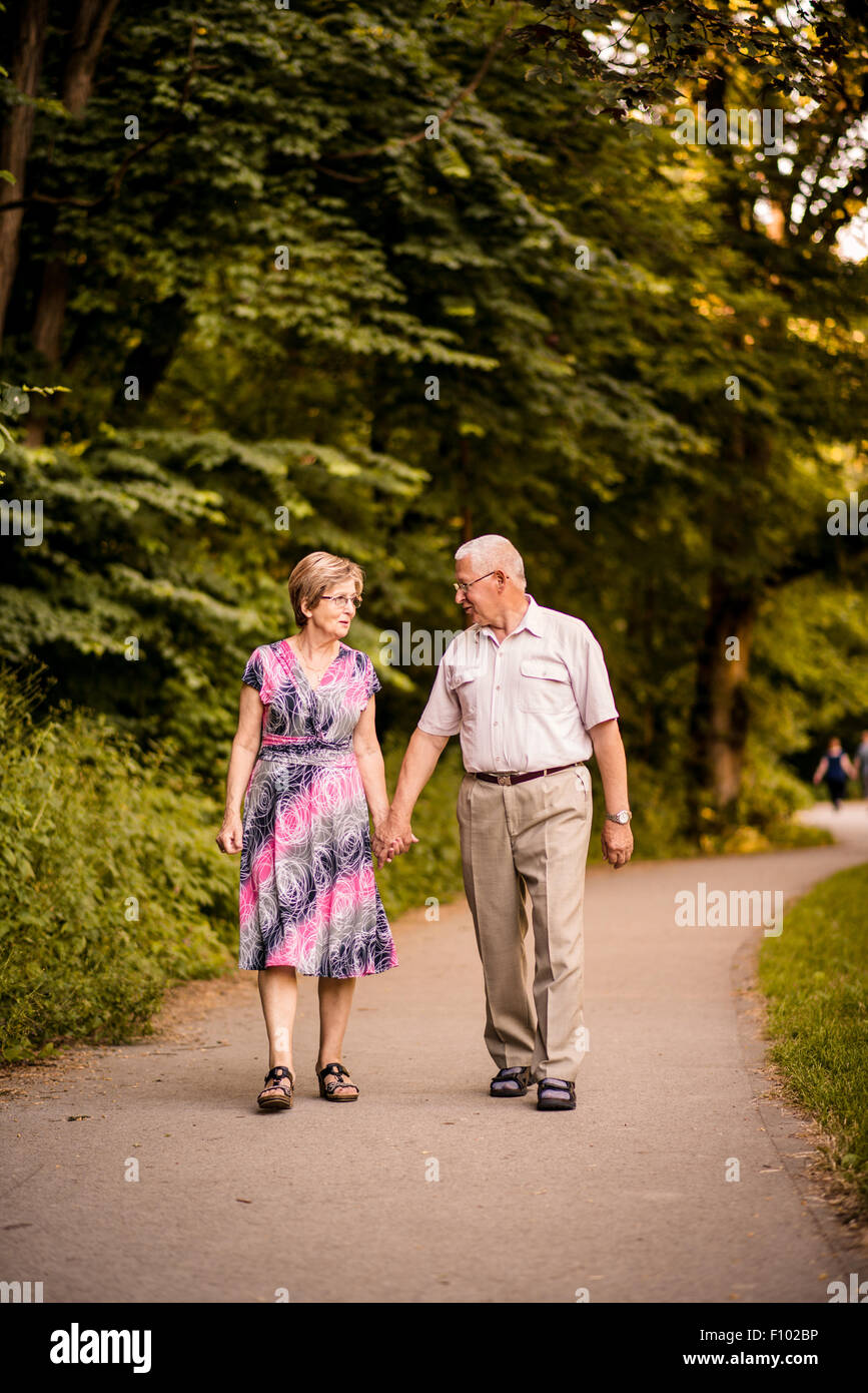 Happy senior couple walking holding hands in forest park Banque D'Images