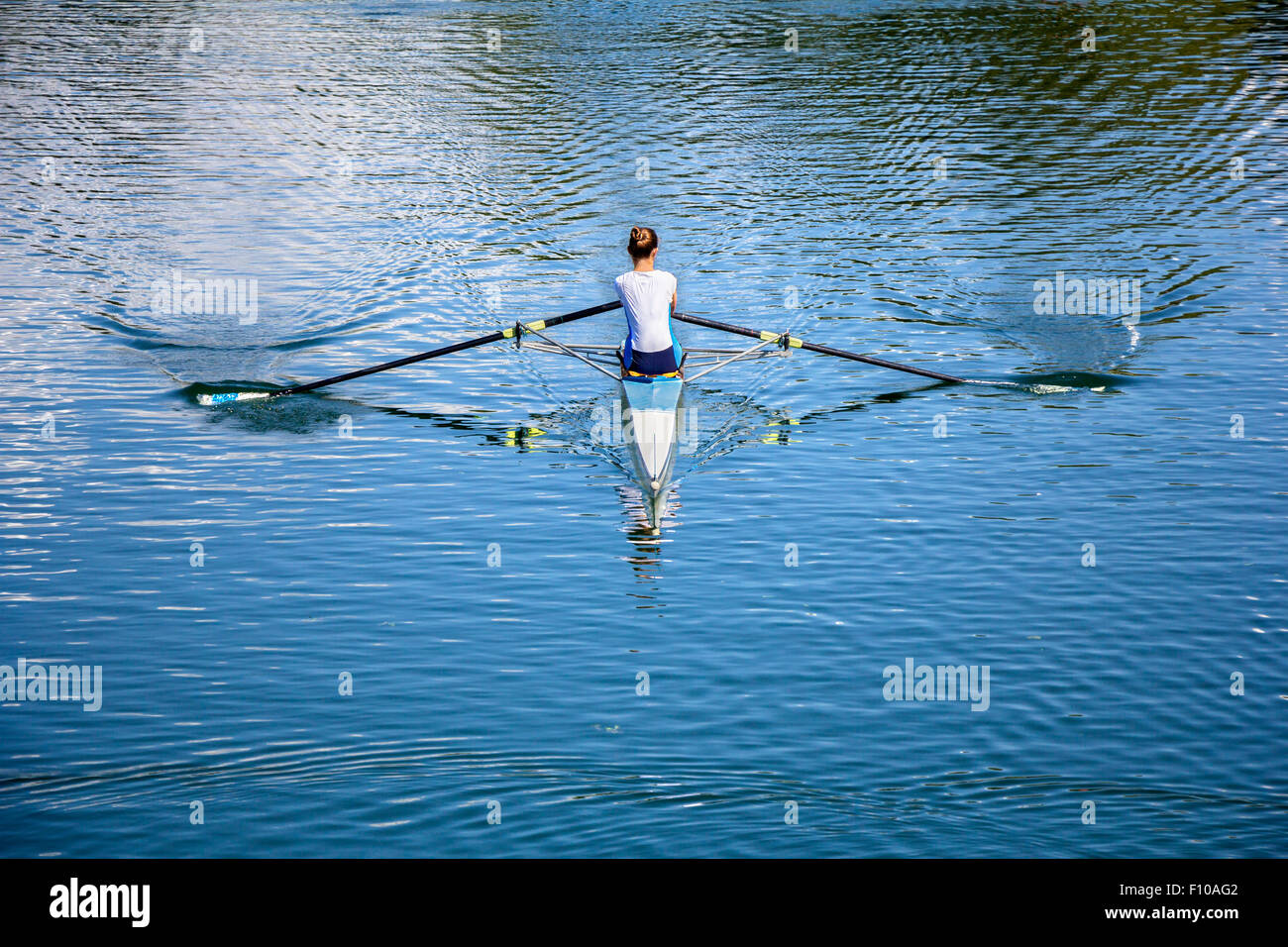 Rameur Femmes dans un bateau, de l'aviron sur le lac tranquille Banque D'Images