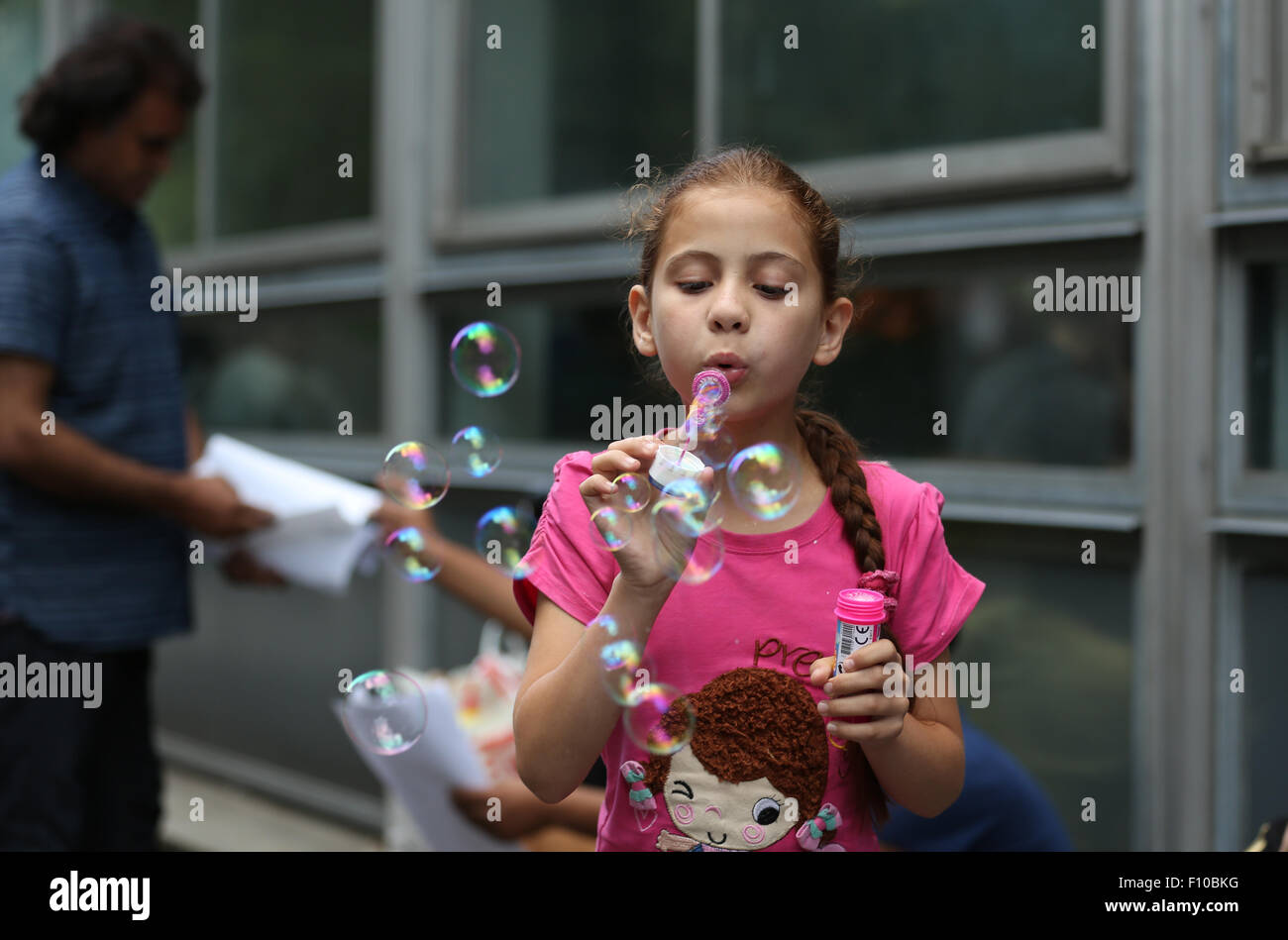 Dortmund, Allemagne. Août 24, 2015. Une fille de la Syrie souffle des bulles de savon à l'avant de l'admission centre de la première installation de réception pour les réfugiés dans la région de Dortmund (Allemagne), 24 août 2015. Le centre d'accueil de Dortmund a atteint sa pleine capacité et n'est pas en mesure de prendre de nouveaux réfugiés. Photo : INA FASSBENDER/dpa/Alamy Live News Banque D'Images