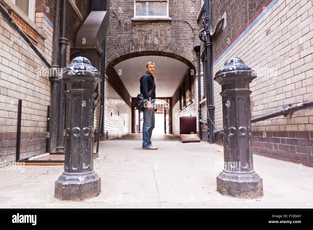 Jeune homme confiant dans les tenues de l'article en milieu urbain qui entoure en face d'un passage dans une ruelle délabrée. Banque D'Images