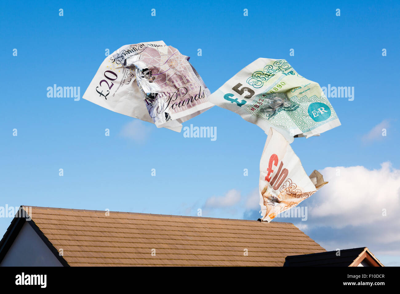 Notes d'argent s'échappant d'un toit de maison pour illustrer les coûts de chauffage des ménages perdre livres de gaspiller de l'argent en espèces la valeur de propriété concept. UK Banque D'Images