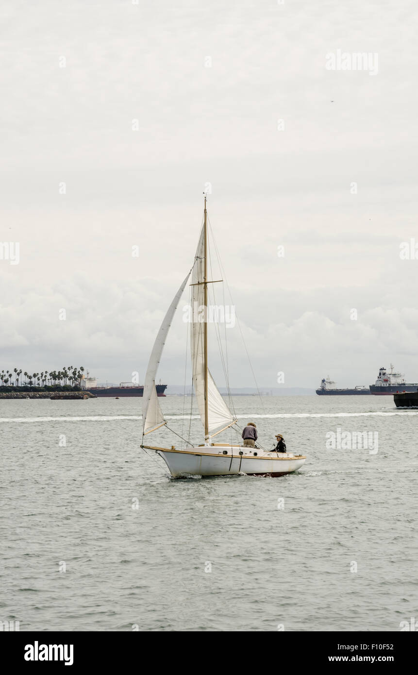 Un sloop voilier côtes le long des eaux calmes du port de Long Beach Banque D'Images