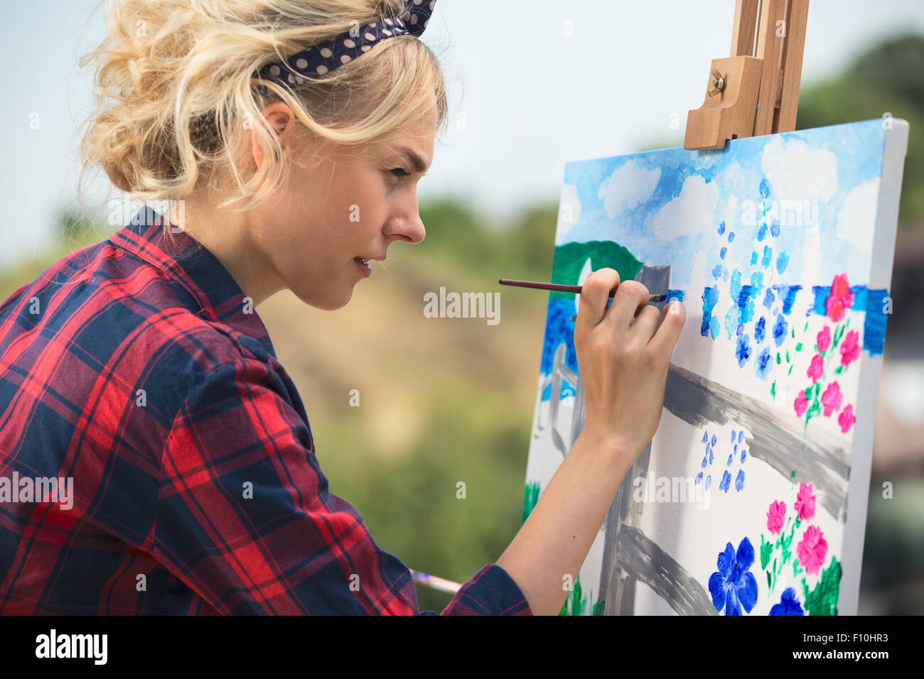 Belle blonde femme artiste peint une image colorée. Banque D'Images