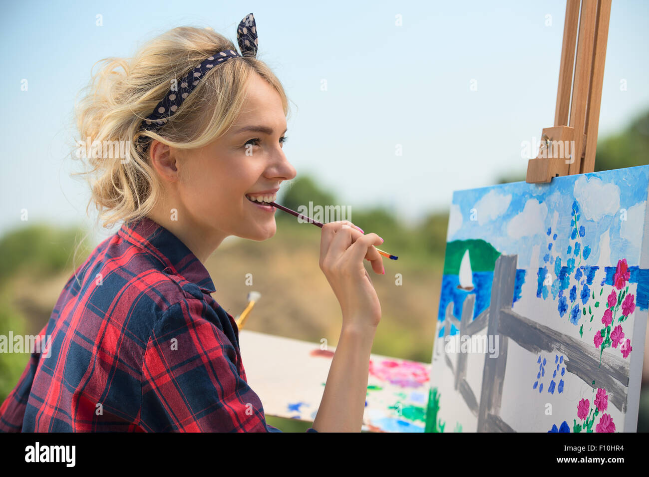 Belle blonde femme artiste peint une image colorée. Banque D'Images