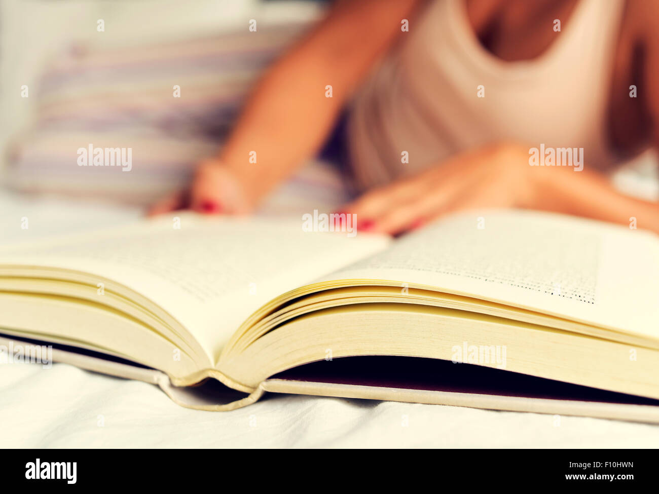 Une jeune femme de race blanche en pyjama de lire un livre au lit Banque D'Images