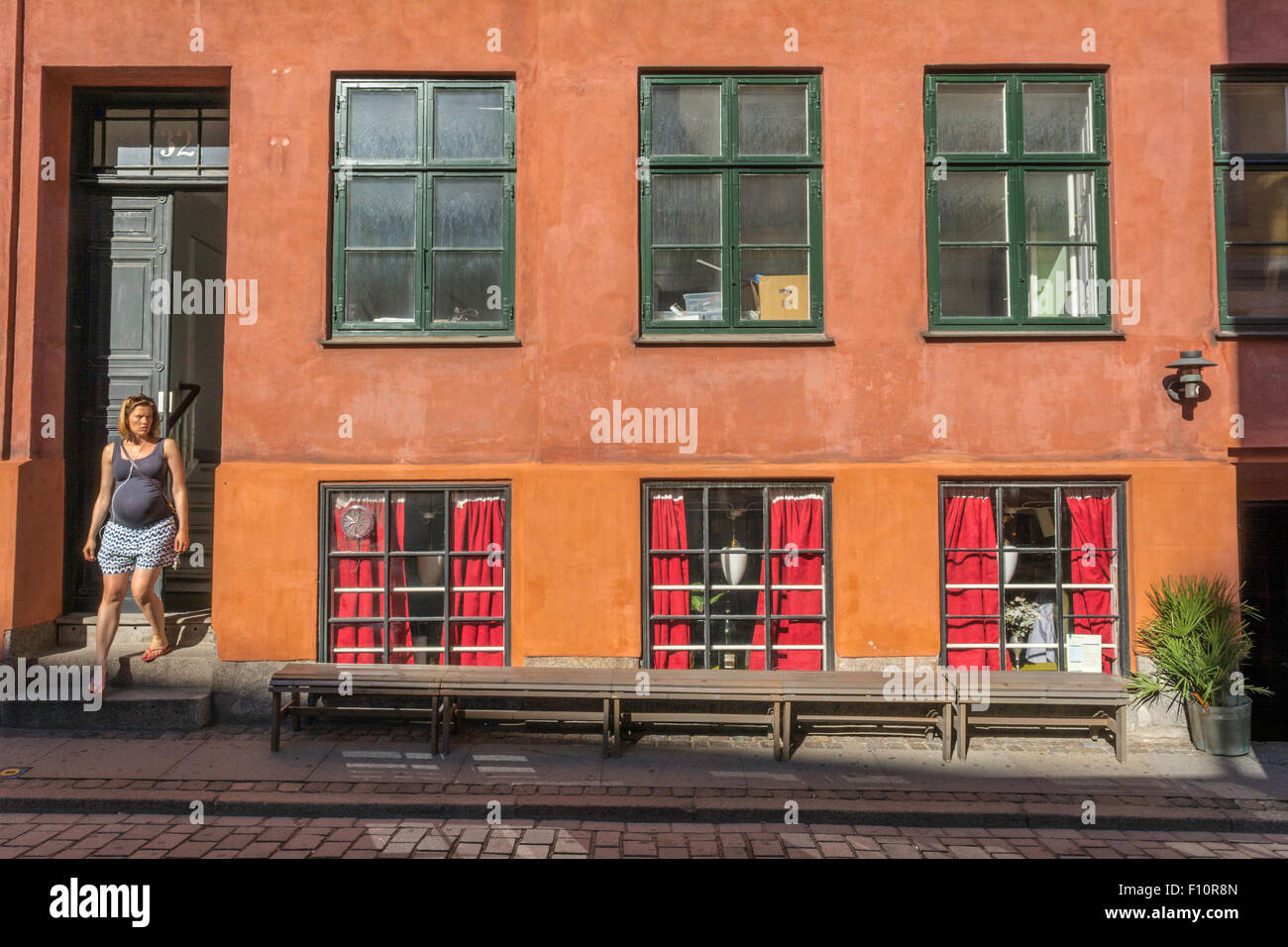 Une femme enceinte émerge d'une porte dans une rue de Copenhague au Danemark, Banque D'Images