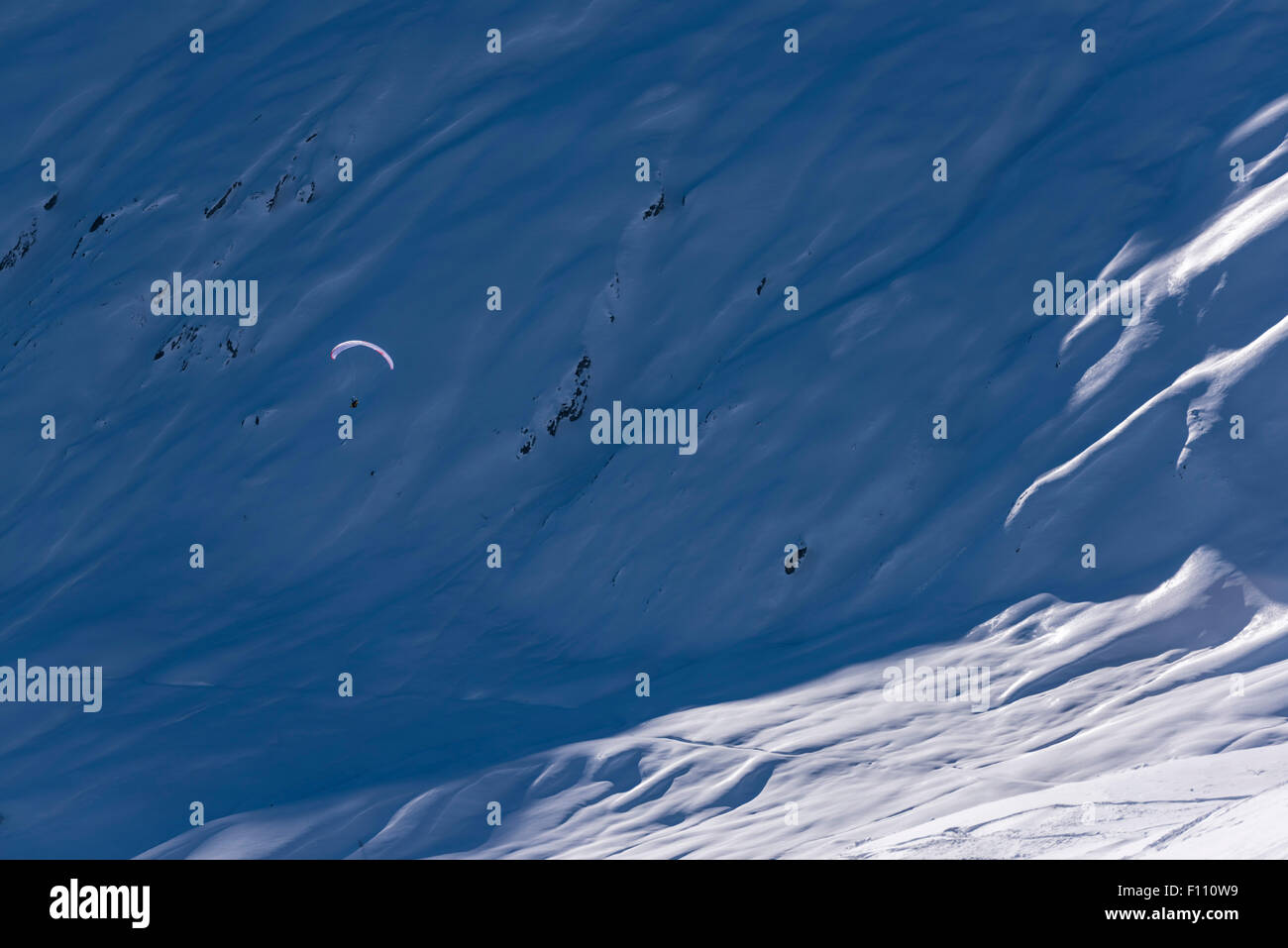 Un parapente vole très haut dans les montagnes couvertes de neige au-dessus d'un névé à Blatten/Belalp, Suisse (canton du Valais). Banque D'Images