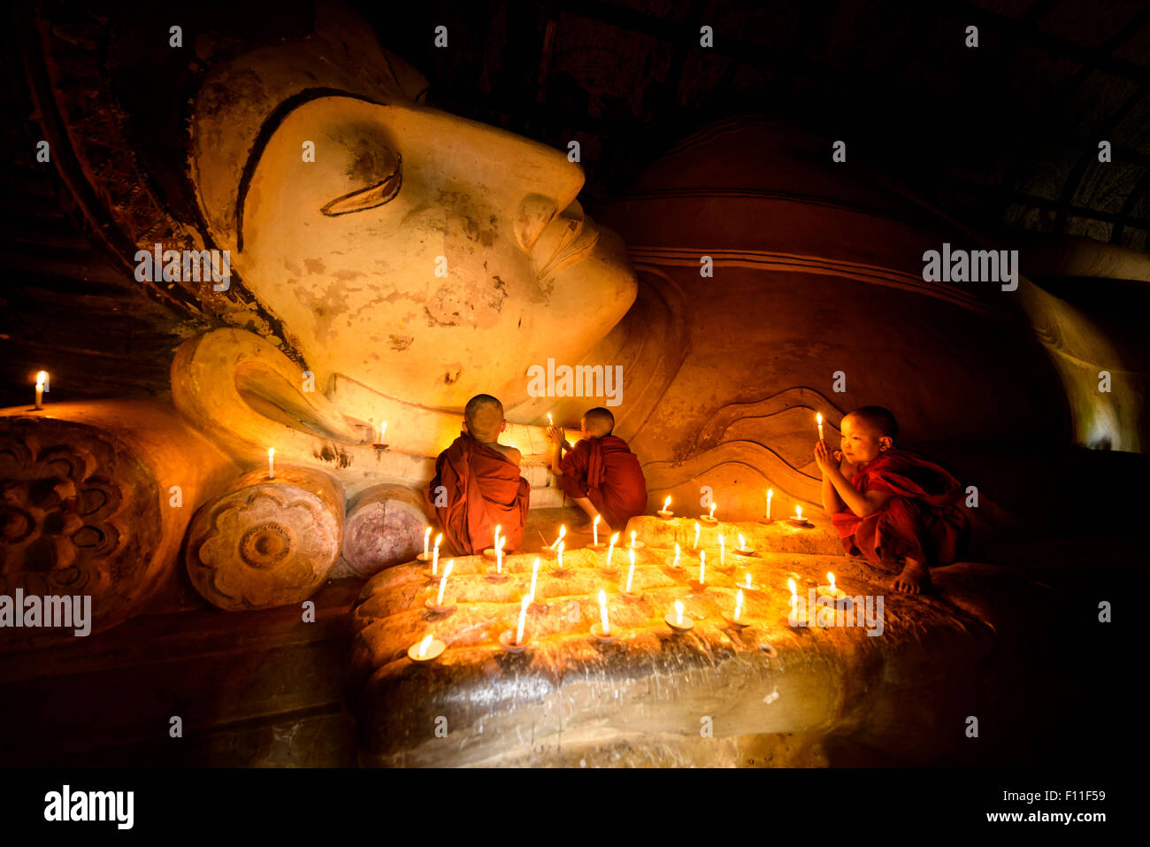 Les moines d'Asie en formation à l'éclairage des bougies statue de Bouddha Banque D'Images