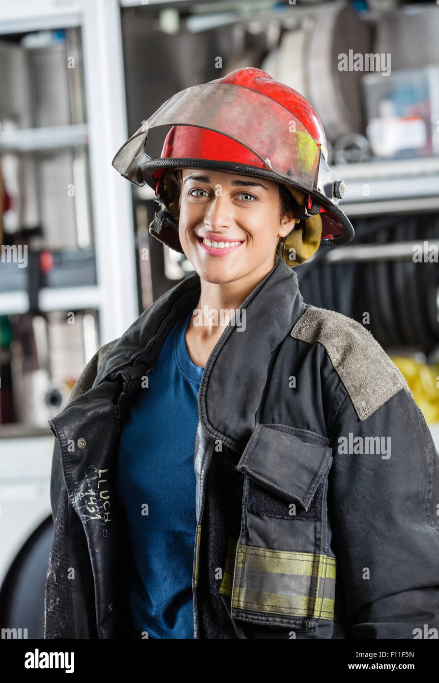 Heureux pompier femelle debout contre les pompiers Banque D'Images