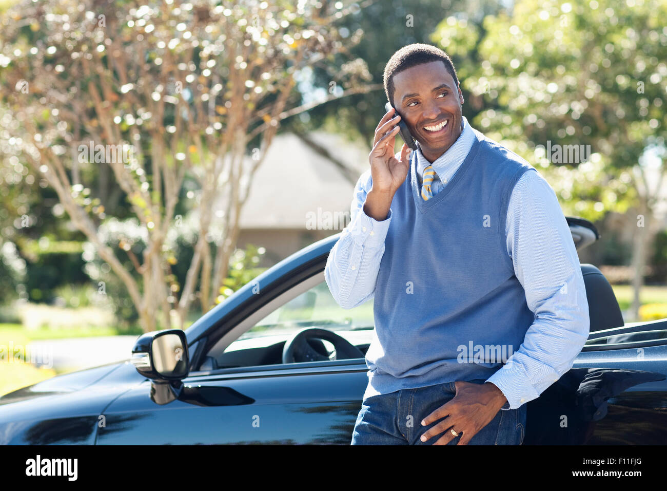 Black man talking on cell phone at convertible Banque D'Images