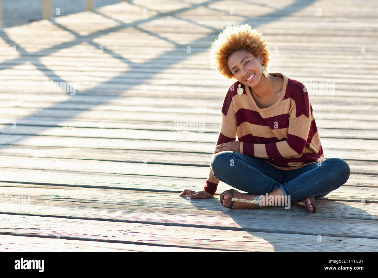 Femme noir assis sur trottoir de bois Banque D'Images