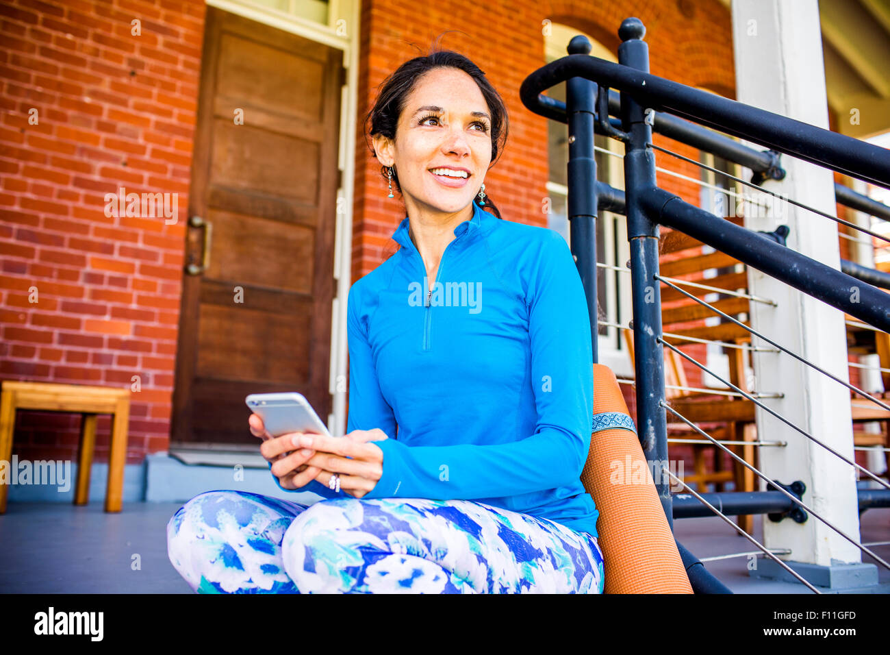 Hispanic woman using cell phone on porch Banque D'Images