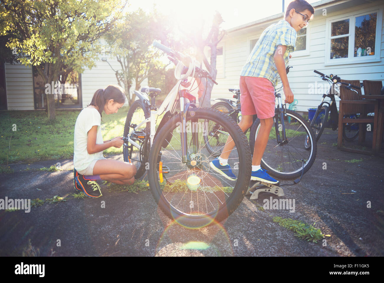 Mixed Race enfants vélos fixation in backyard Banque D'Images