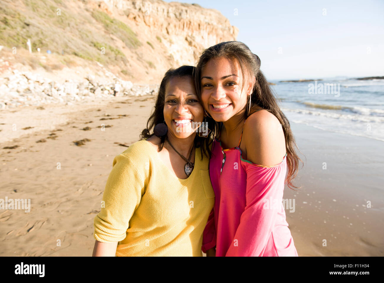 African American mother and daughter smiling on beach Banque D'Images