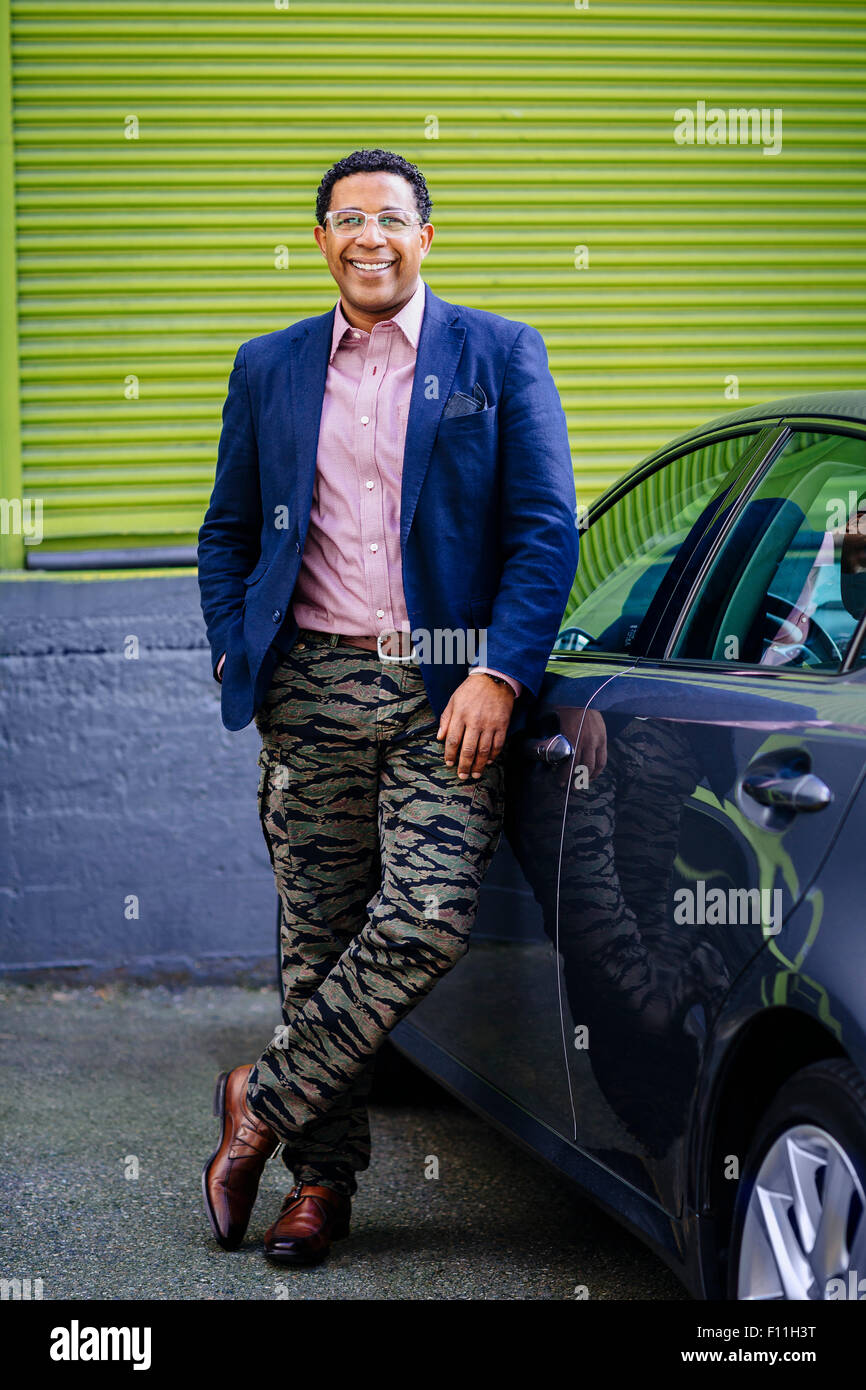 Élégant mixed race businessman leaning on car Banque D'Images