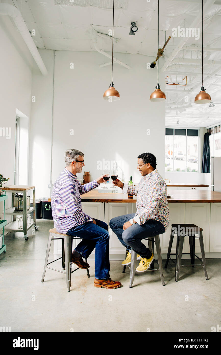 Gay couple toasting with wine at counter Banque D'Images
