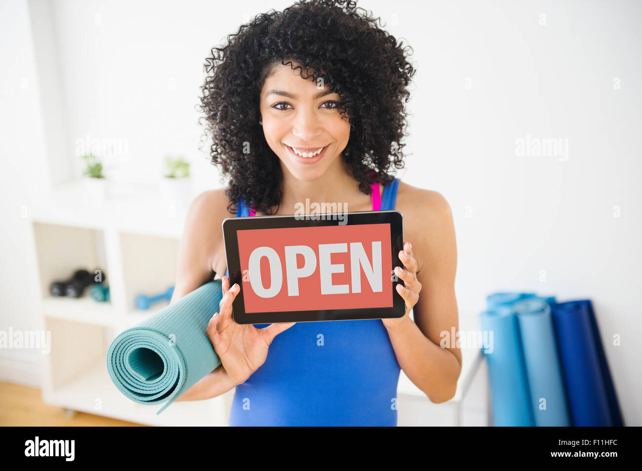 Mixed Race woman holding open sign in yoga studio Banque D'Images