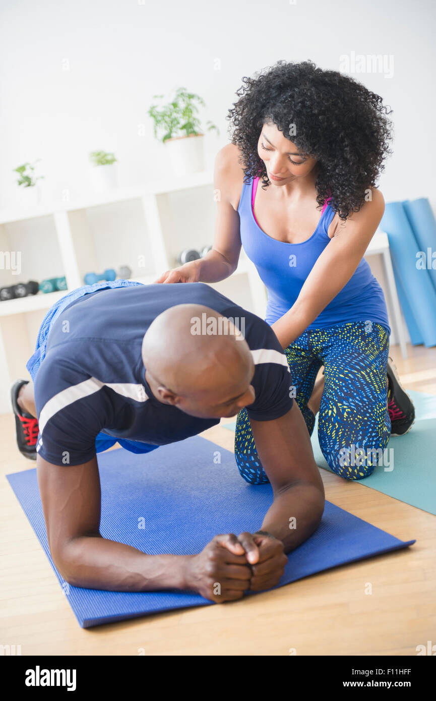 L'homme travaillant avec formateur dans une salle de sport Banque D'Images