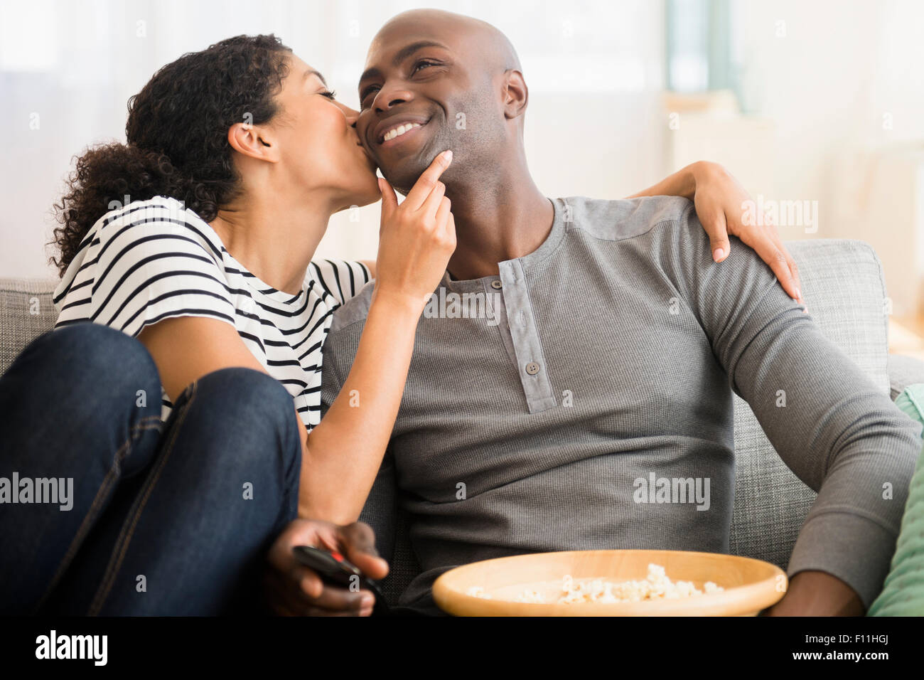 Smiling couple watching television on sofa Banque D'Images