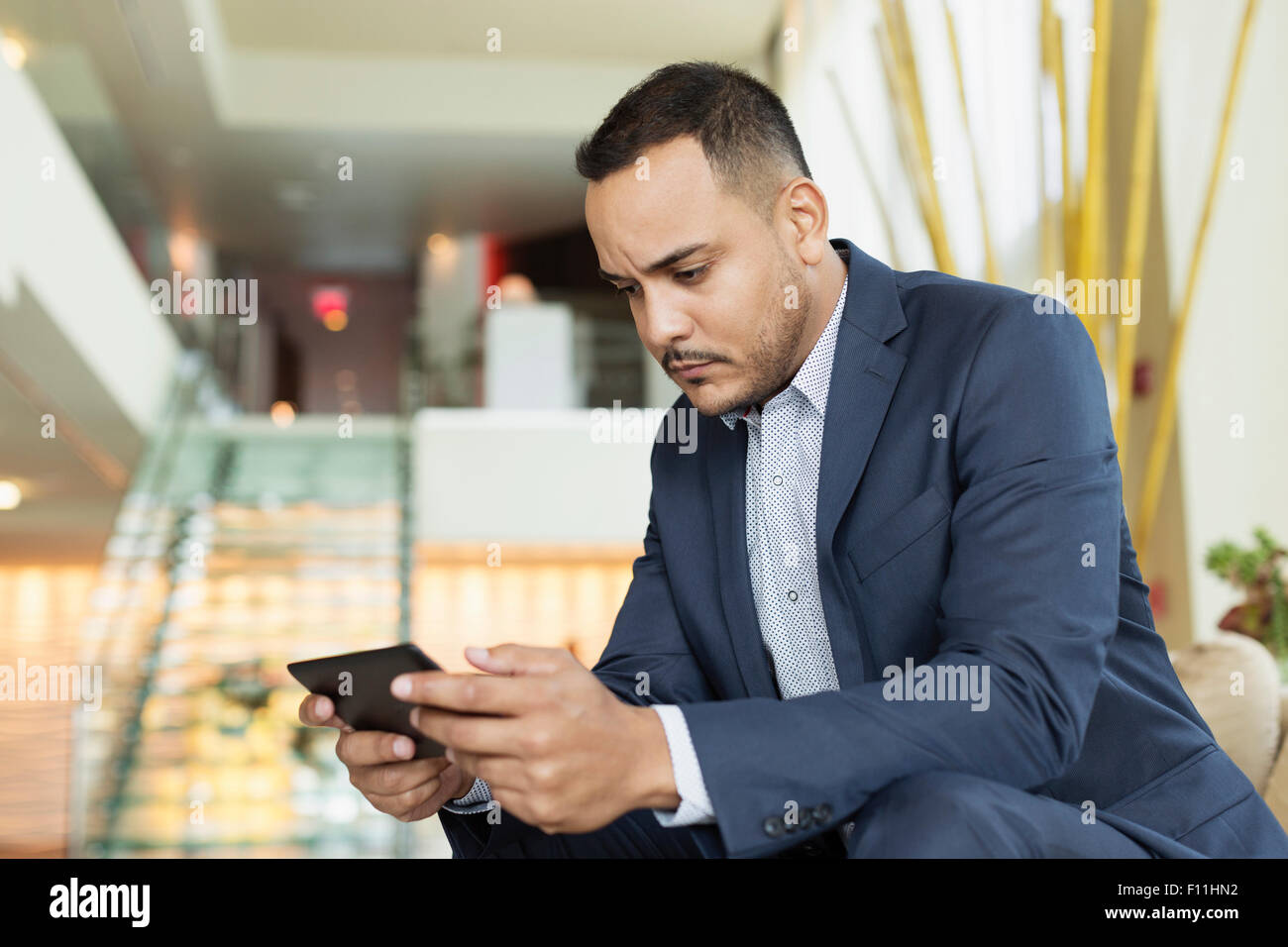 Hispanic businessman using digital tablet in hotel lobby Banque D'Images