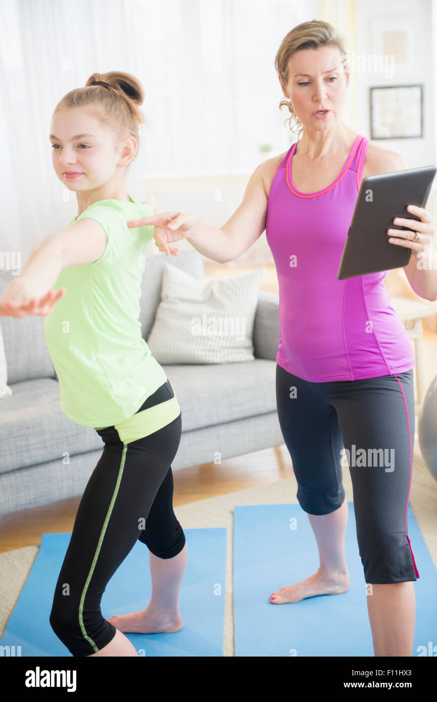 Caucasian mother and daughter practicing yoga with digital tablet Banque D'Images