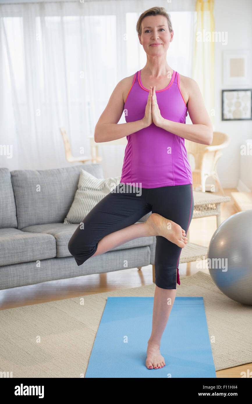 Caucasian woman practicing yoga in living room Banque D'Images