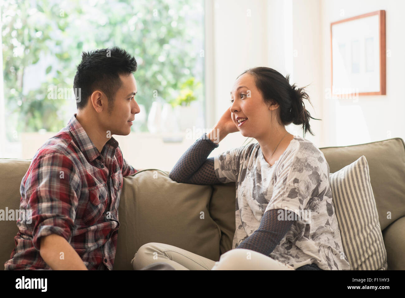 Couple talking on sofa in living room Banque D'Images