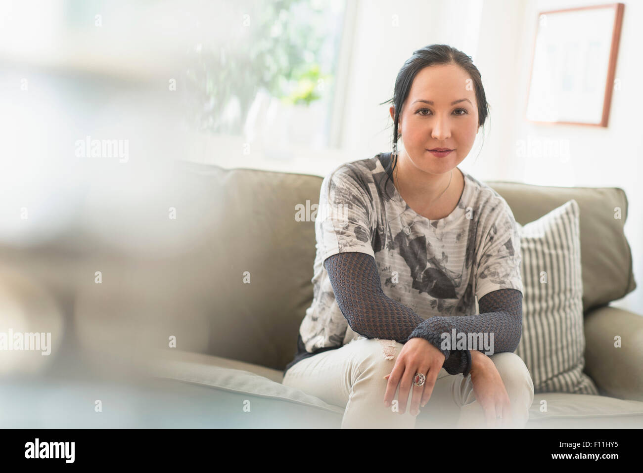 Mixed Race woman sitting on sofa in living room Photo Stock - Alamy