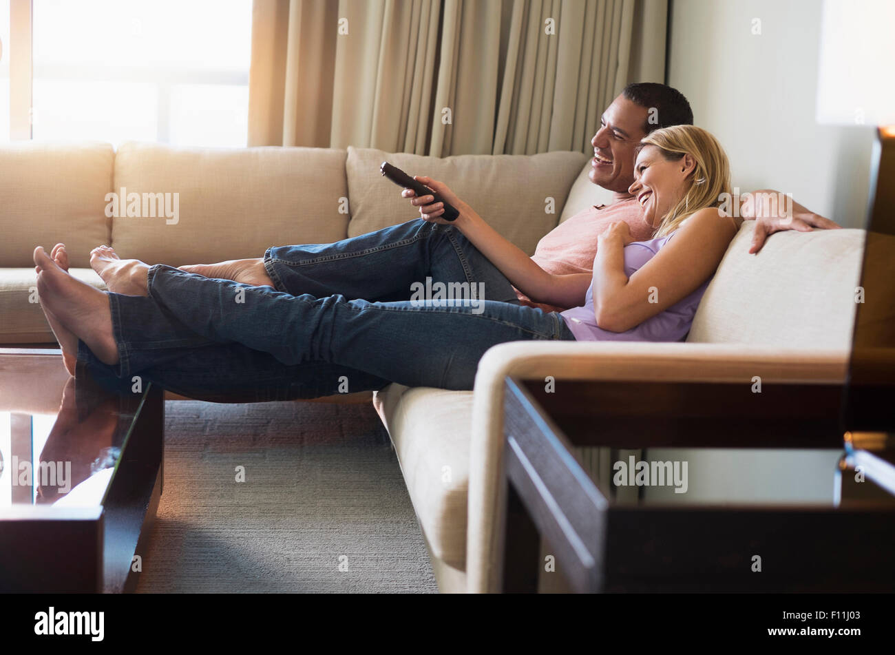 Couple watching television on sofa Banque D'Images