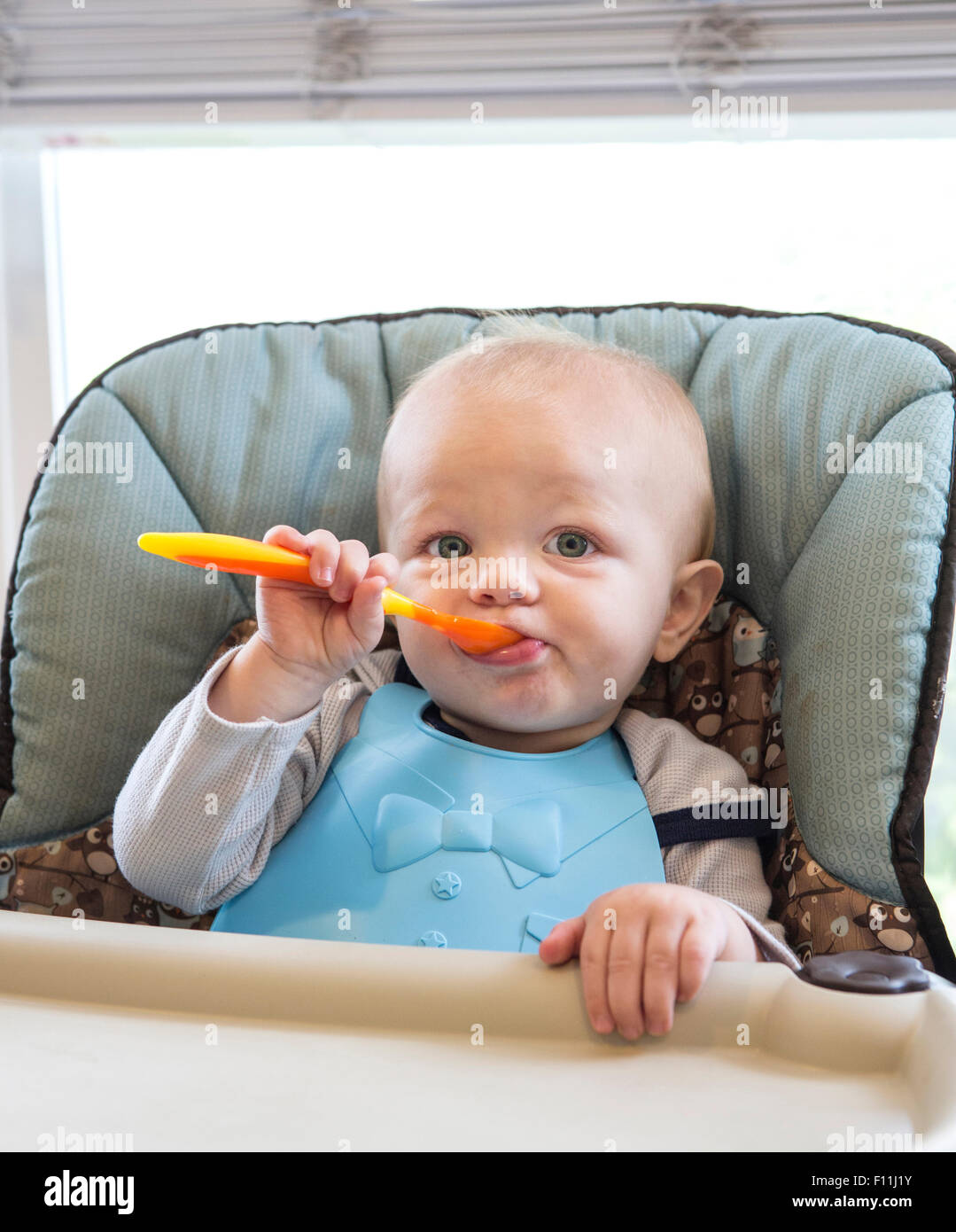 Caucasian baby boy eating dans une chaise haute Banque D'Images