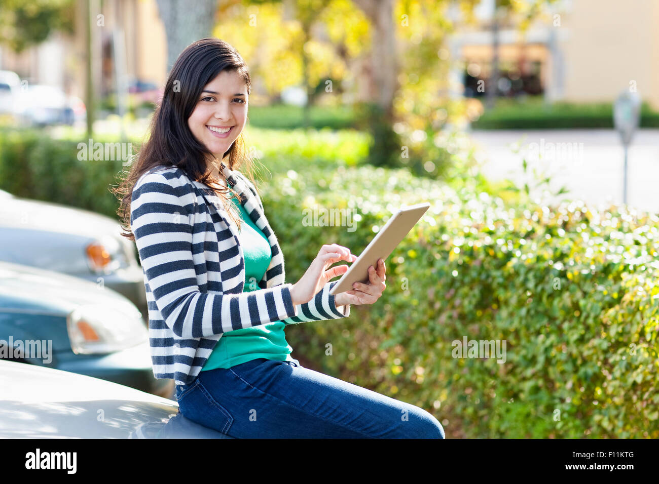 Hispanic woman using digital tablet in parking lot Banque D'Images