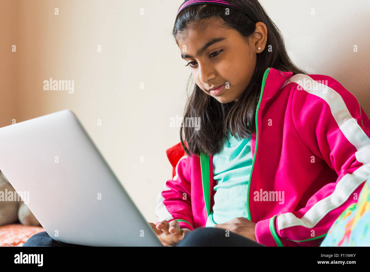 Indian girl using laptop on bed Banque D'Images