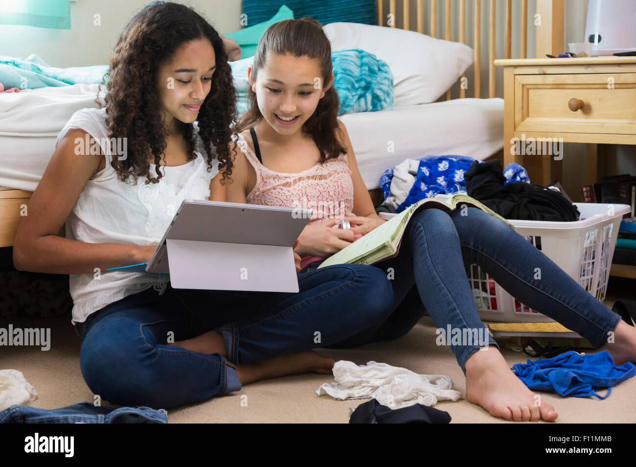 Teenage Girls using digital tablet in bedroom Banque D'Images