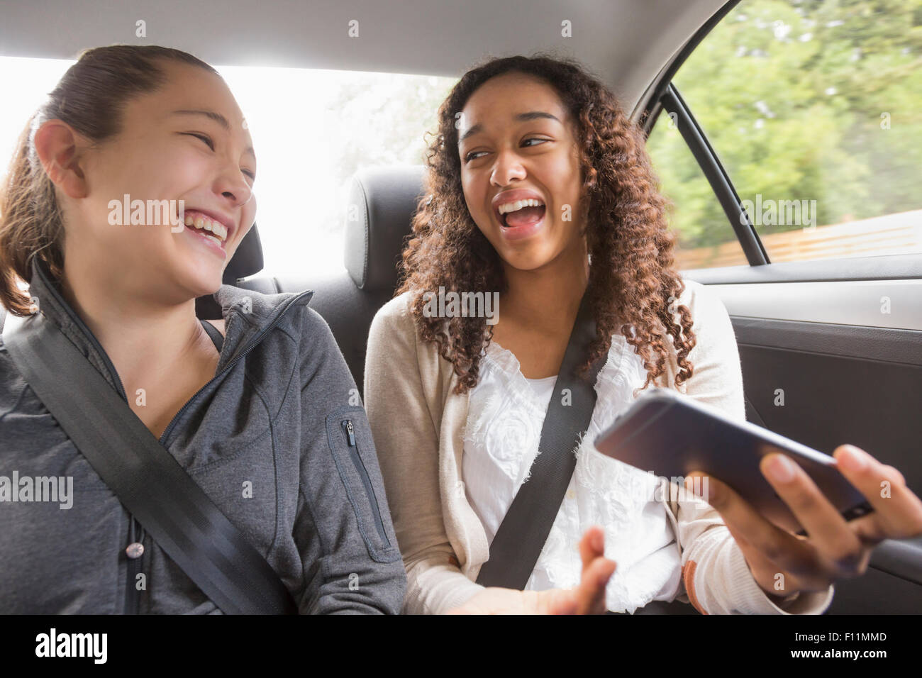 Teenage Girls using cell phone in car siège arrière Banque D'Images